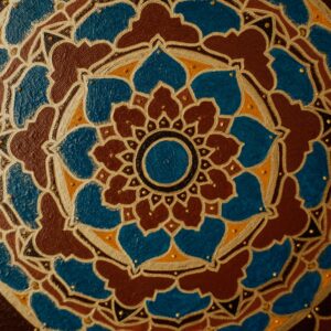 Detailed close-up of a mandala artwork with blue, brown, and gold patterns showcasing ornamental symmetry.